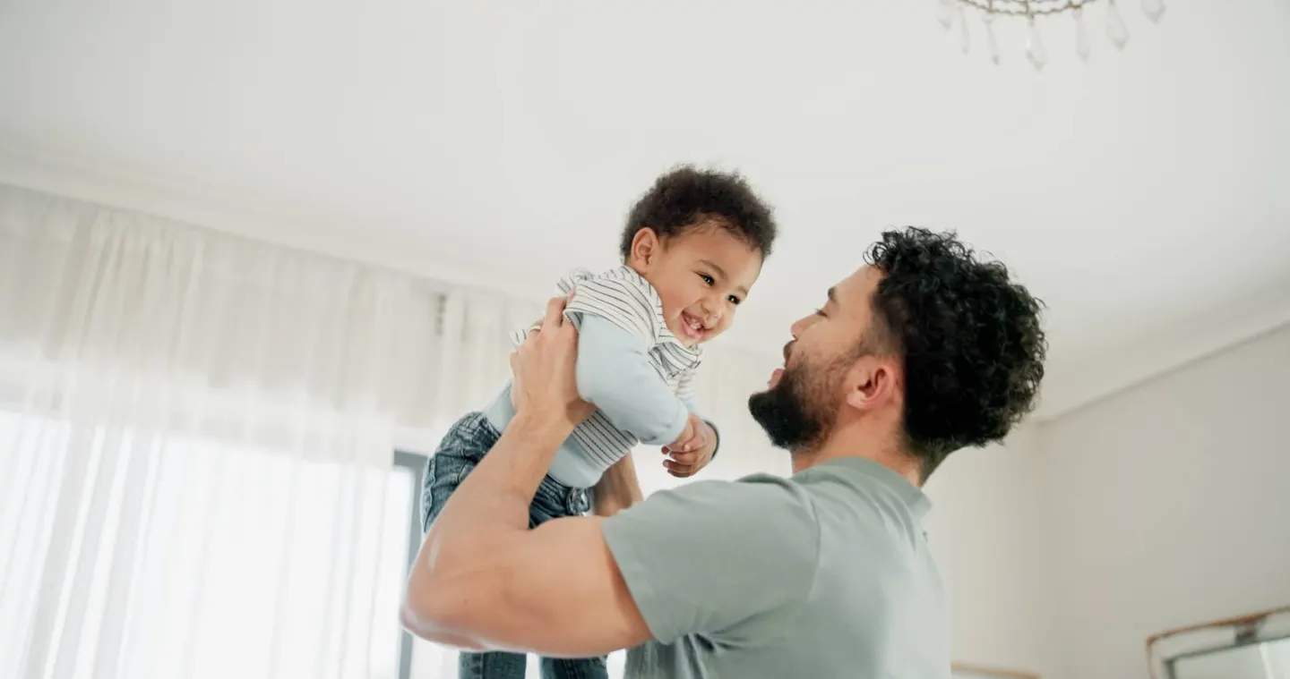 A dad lifting his baby into the air